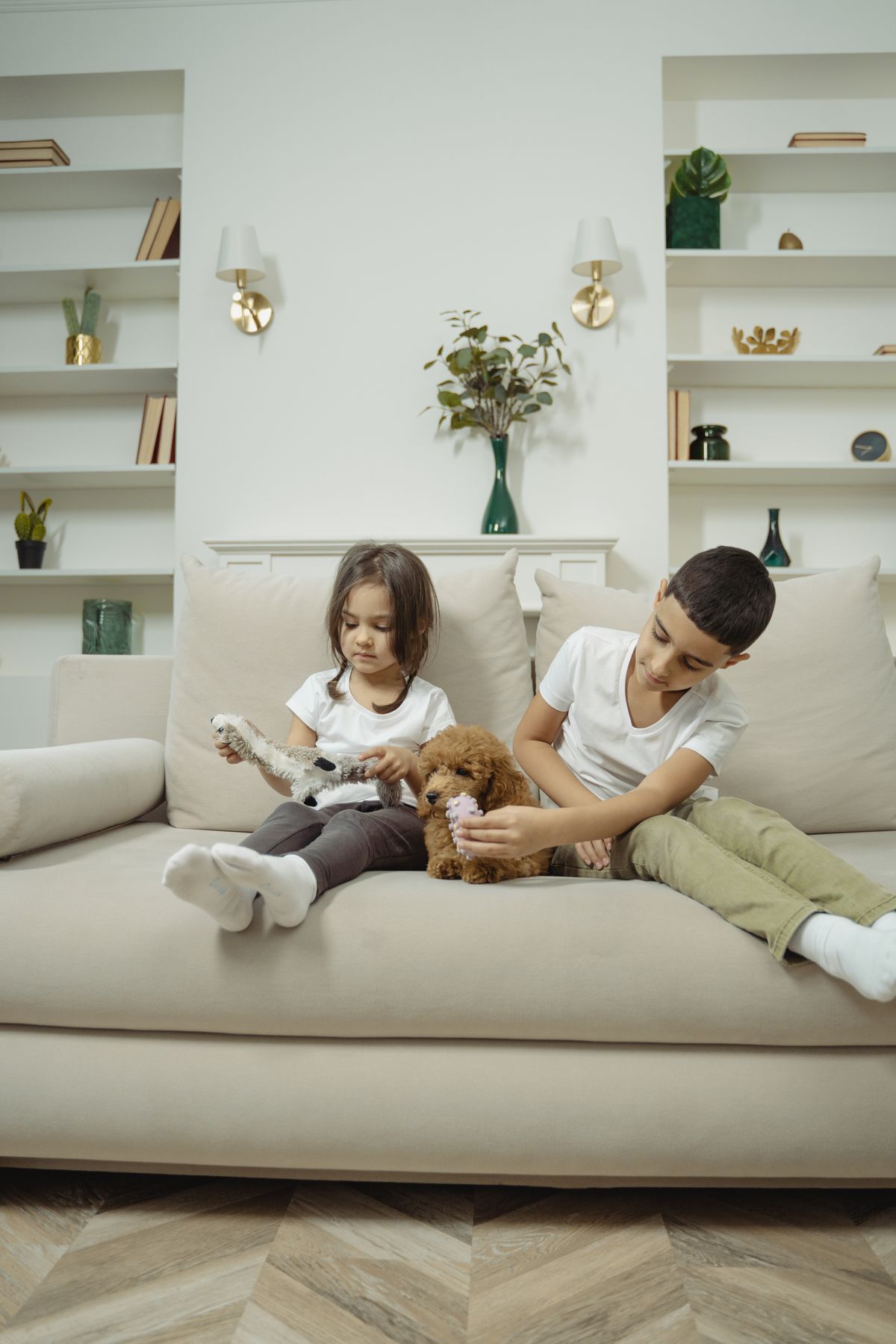 Two children bonding with a puppy on a sofa